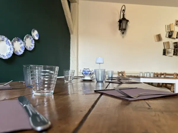 Table dressée en bois, verres et assiettes bleues au mur
